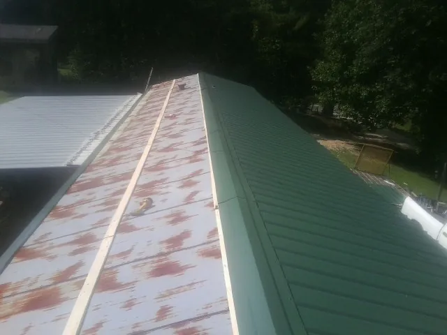Old rusted panels beside newly installed green metal roofing — Wind Damage Roof Repair by Roofing Brothers in Peshtigo