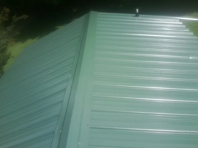 New green metal panels meeting at the ridge of a roof — Flat Roof Repair work by our crew in Peshtigo