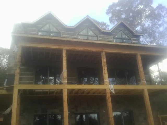 Dormers and porch framing on a large log home under construction — Roof Coating work by our crew in Peshtigo