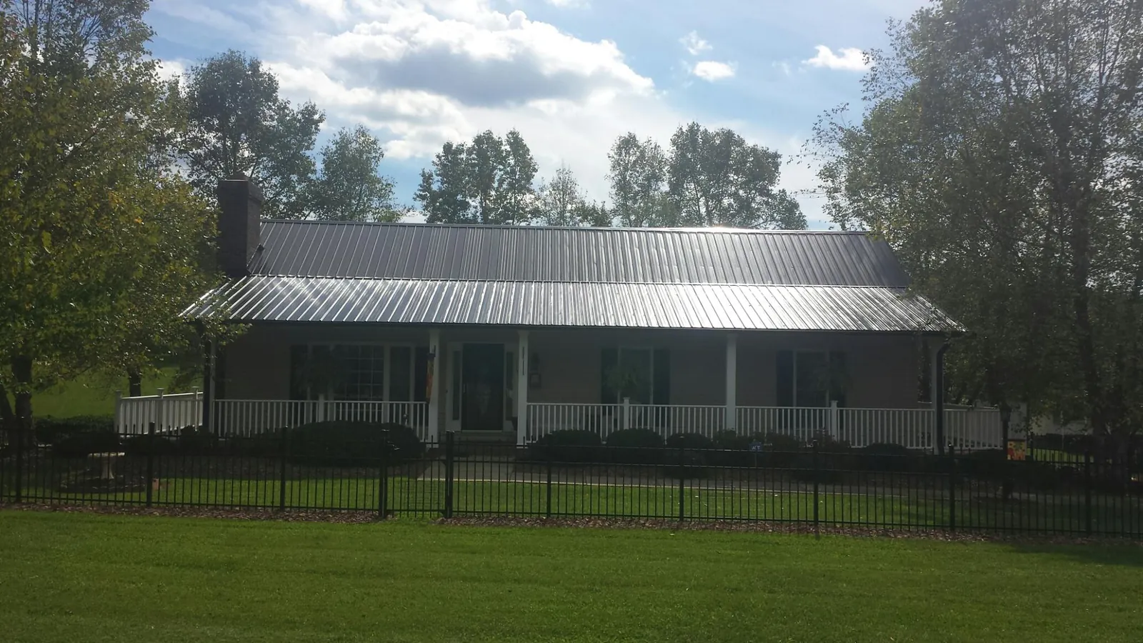 Gray metal roof on a brick ranch with a full width front porch — Gutter Guard Installation work by our crew in Peshtigo